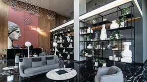 Un vestíbulo moderno con un sofá gris, mesas redondas y una amplia estantería llena de objetos decorativos.