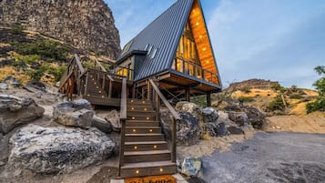 A modern building with a steep roof, wooden staircase, and a welcome mat.