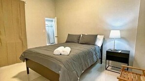 Une chambre à coucher avec un lit, une table de chevet avec une lampe et un banc en bois.