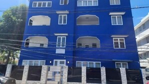 Un immeuble à plusieurs étages, doté d’une façade bleue et de fenêtres à encadrement blanc.