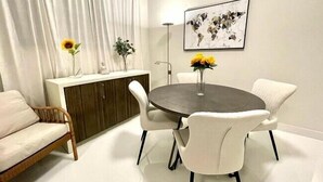 Un espace repas moderne avec une table ronde, des chaises blanches et un vase rempli de fleurs jaunes.