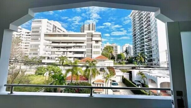 Un balcon offrant une vue sur des bâtiments modernes et un ciel dégagé.