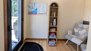A room with a black door, a map on the wall, a bookshelf, a patterned chair, and a ceiling light fixture. - Cool City Motel  (Two Rivers)