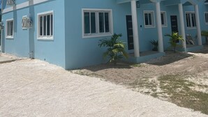 Una casa de dos pisos con fachada azul claro, múltiples ventanas y un camino de entrada de grava.