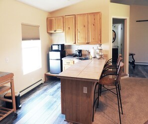 A kitchen with wooden cabinets, a refrigerator, a microwave, a coffee maker, and a sink. - Charming country studio close to Fruita and biking trails (Fruita)