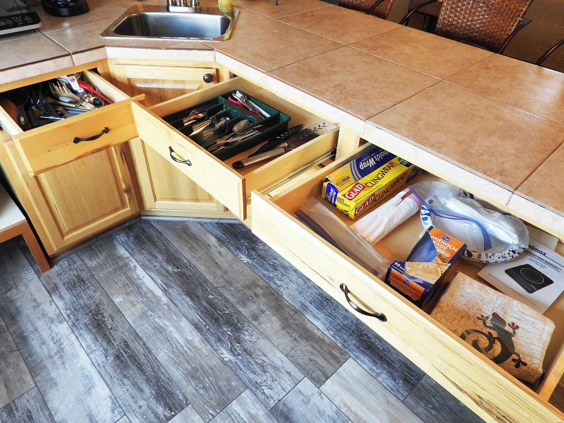 A kitchen with a built-in drawer unit containing various kitchen tools and supplies.