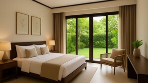 Een hotelkamer met een groot bed, twee bedlampen, een stoel, een bureau en uitzicht op een weelderige tuin door een schuifdeur van glas.