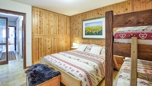 A wooden-paneled room with a bed, a wooden bench, and a framed picture of sunflowers. - 2 bedroom lovely apartment in Ponte di Legno (Ponte di Legno)