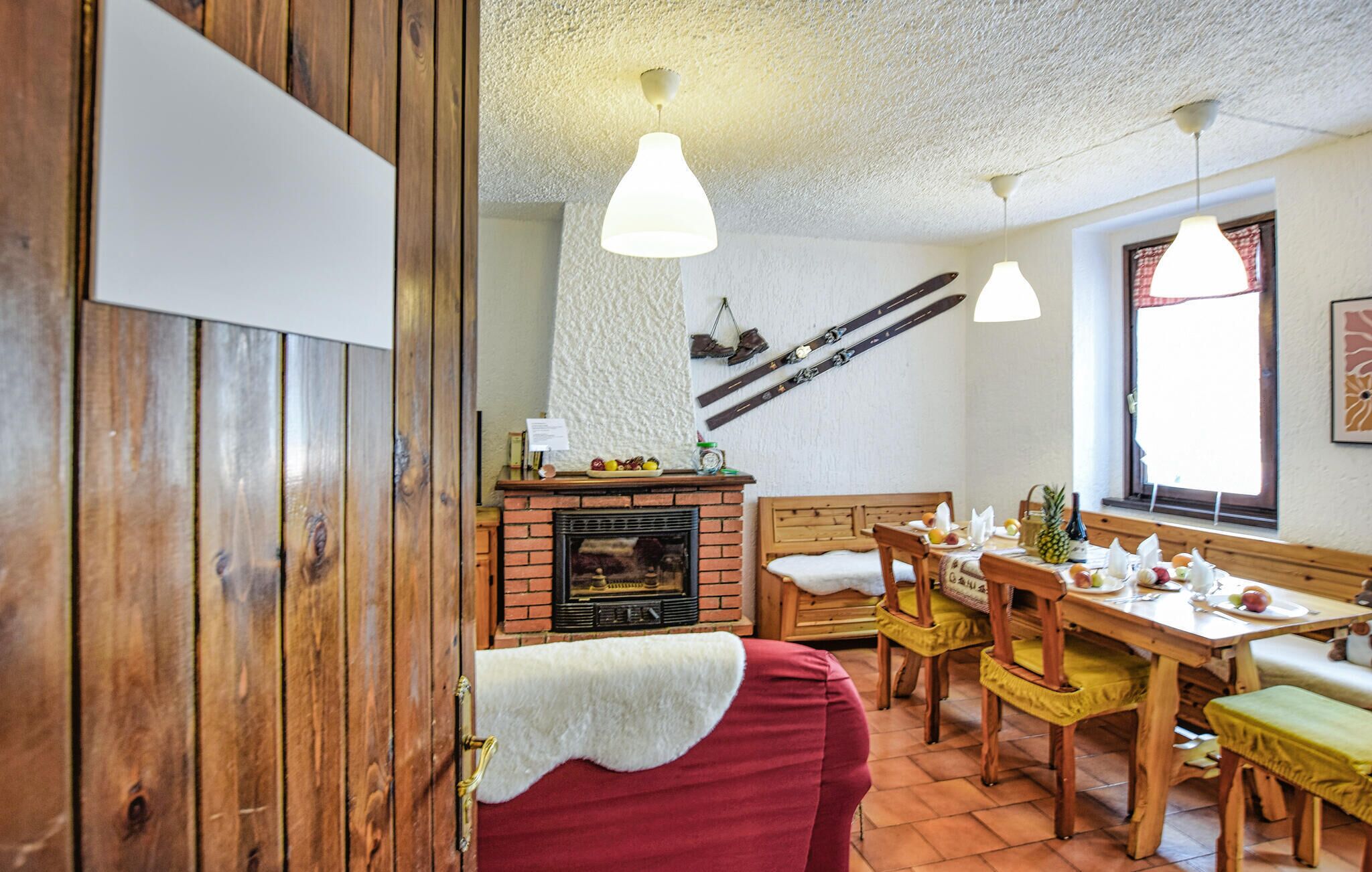 A cozy room with a fireplace, wooden furniture, and hanging skis.