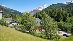 A mountain village with traditional houses, a paved road, and a car parked near a building. - 2 bedroom lovely apartment in Ponte di Legno (Ponte di Legno)
