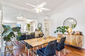 Un comedor moderno con una mesa de madera, sillas negras y un espejo grande.