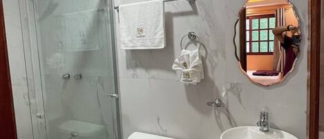 Un baño moderno con ducha de vidrio, inodoro, lavabo y espejo con vistas al exterior.