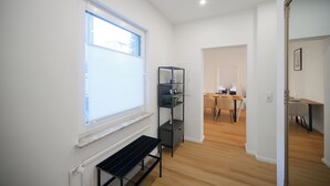 Een modern interieur met een raam, een zwart schap, een eethoek met tafel en stoelen, en een spiegel.
