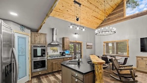 Una cocina moderna con armarios de madera, una isla central y un comedor con una mecedora de madera.