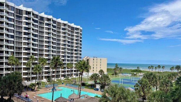 Un hotel con varios pisos, piscina y vista al mar.
