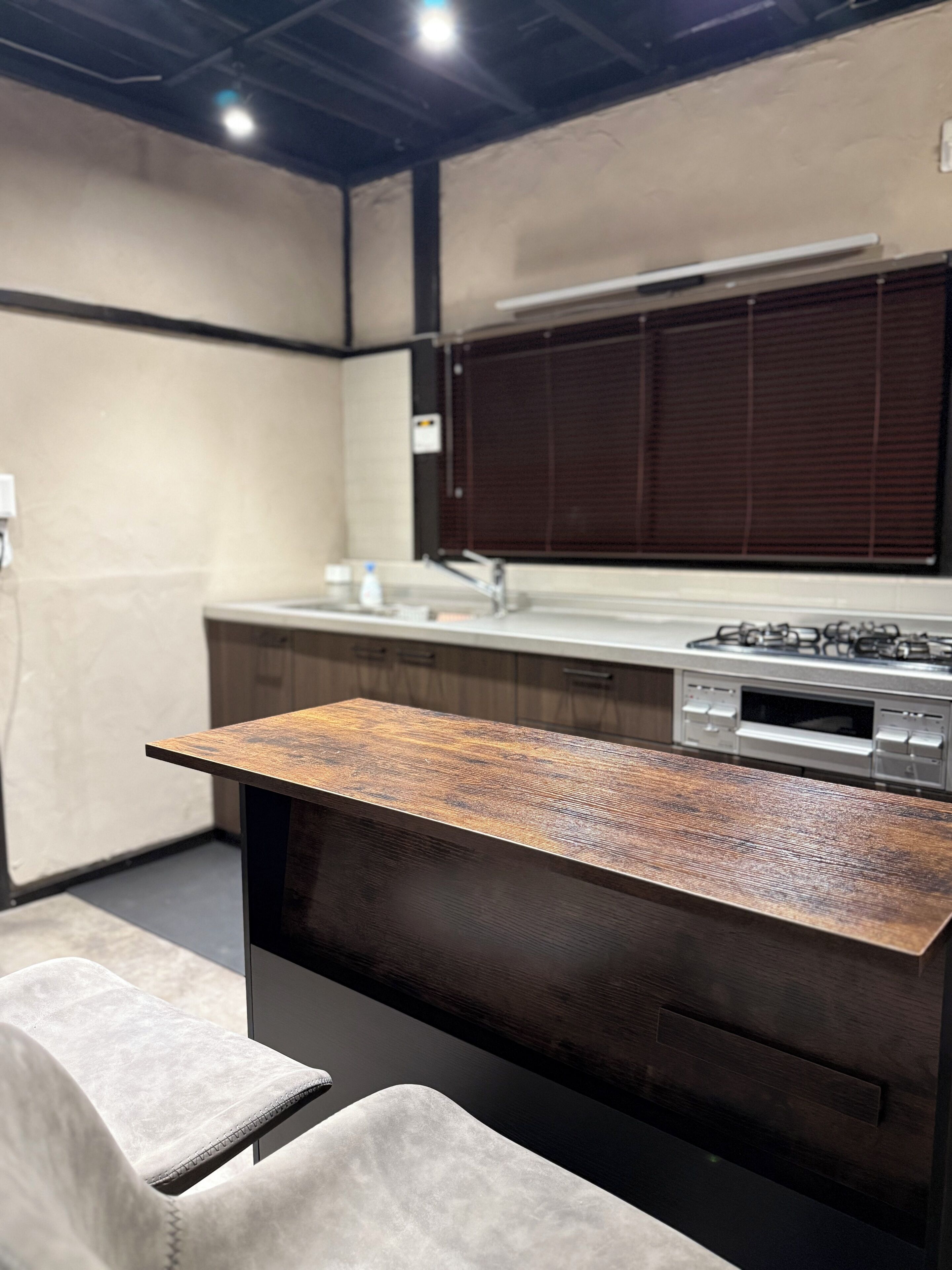A modern kitchen with a wooden countertop, a built-in oven, and a window with blinds.