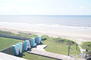 A beach view with a wooden walkway leading to large white letters spelling 'WALK'.