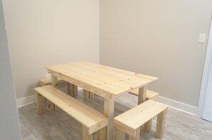 A wooden table with benches in a room with plain walls and a light-colored floor.