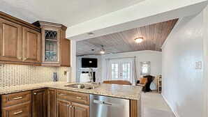 Una cocina con armarios de madera, lavavajillas de acero inoxidable y encimera de granito.