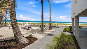 A beachside patio with palm trees, a bench, and a view of the ocean. - Beachfront Condo | Pool, Pickleball, Tennis & More! (Bonita Springs)