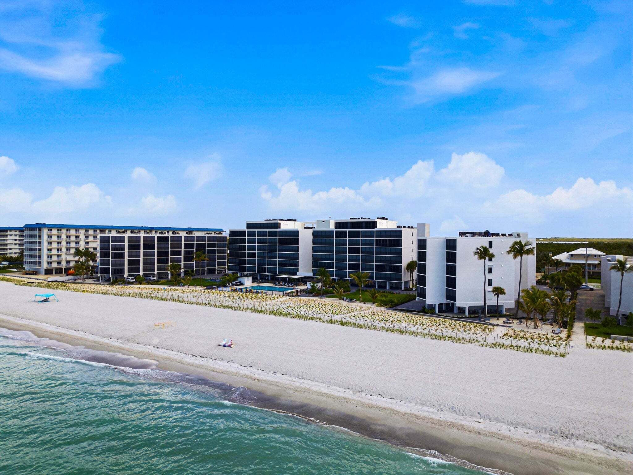 A beachfront hotel with multiple buildings, a sandy beach, and a pool area.