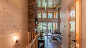 Un interior de madera con una escalera, un banco y vistas al exterior.