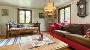 A cozy living room with a wooden coffee table, a red sofa, a plaid sofa, and a chandelier.