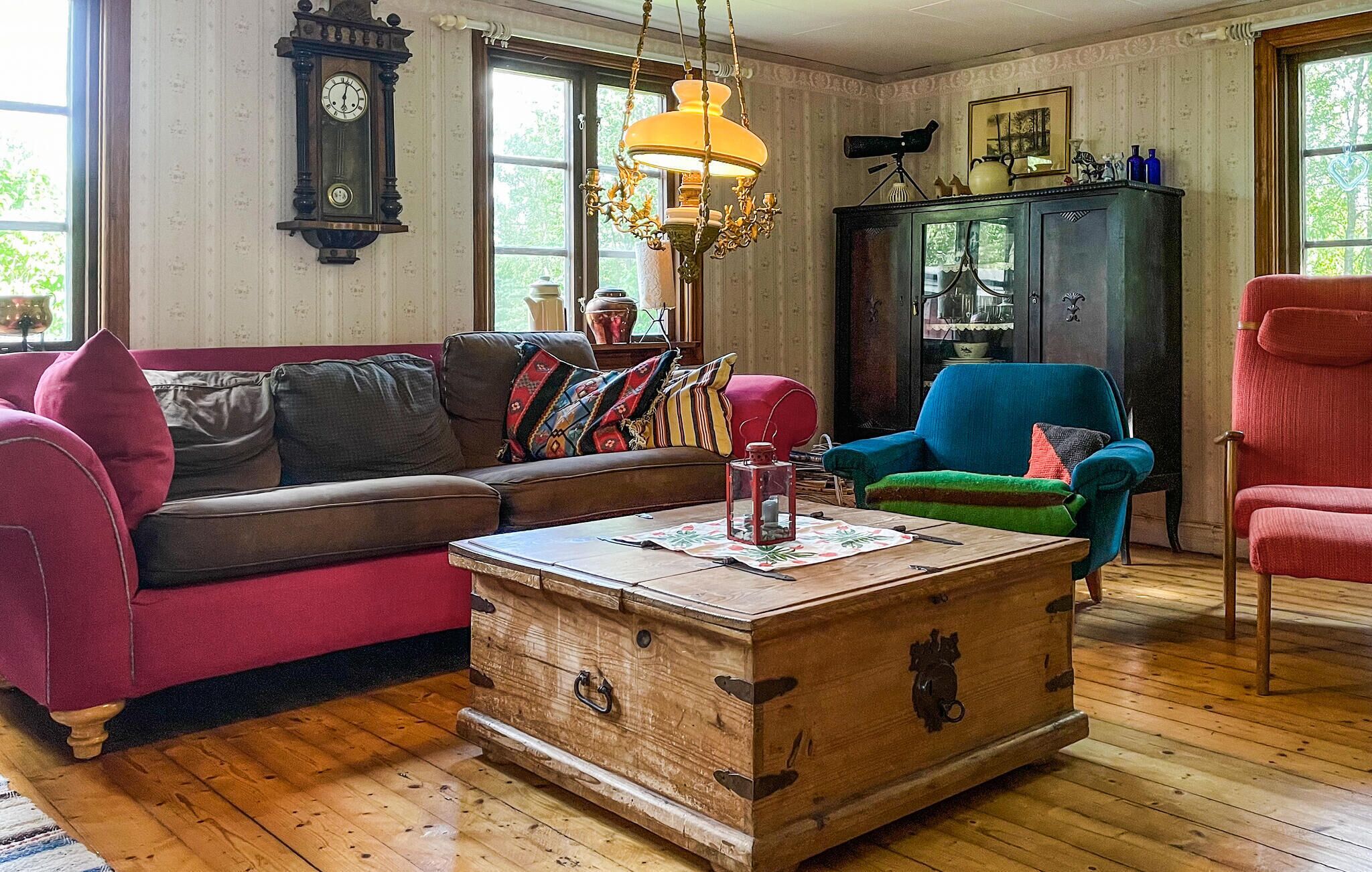 Un salón acogedor con una mesa de centro de madera, un sofá marrón, un sillón azul y un sillón rojo.
