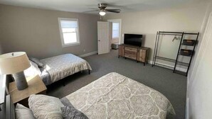 A bedroom with two beds, a ceiling fan, a TV, a dresser, and a walk-in closet. - 3 Br Gem in Downtown Mooresville (Mooresville)