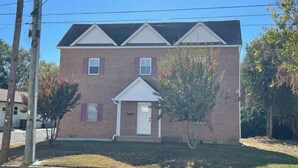 A two-story brick building with a central entrance and a small porch. - 3 Br Gem in Downtown Mooresville (Mooresville)