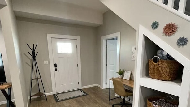 A spacious hallway with a wooden floor, a staircase with white balusters, and a white wall with decorative flowers. - 3 Br Gem in Downtown Mooresville (Mooresville)
