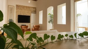 Ein Wohnzimmer mit Steinkamin, Flachbildfernseher, Sofa und Couchtisch.