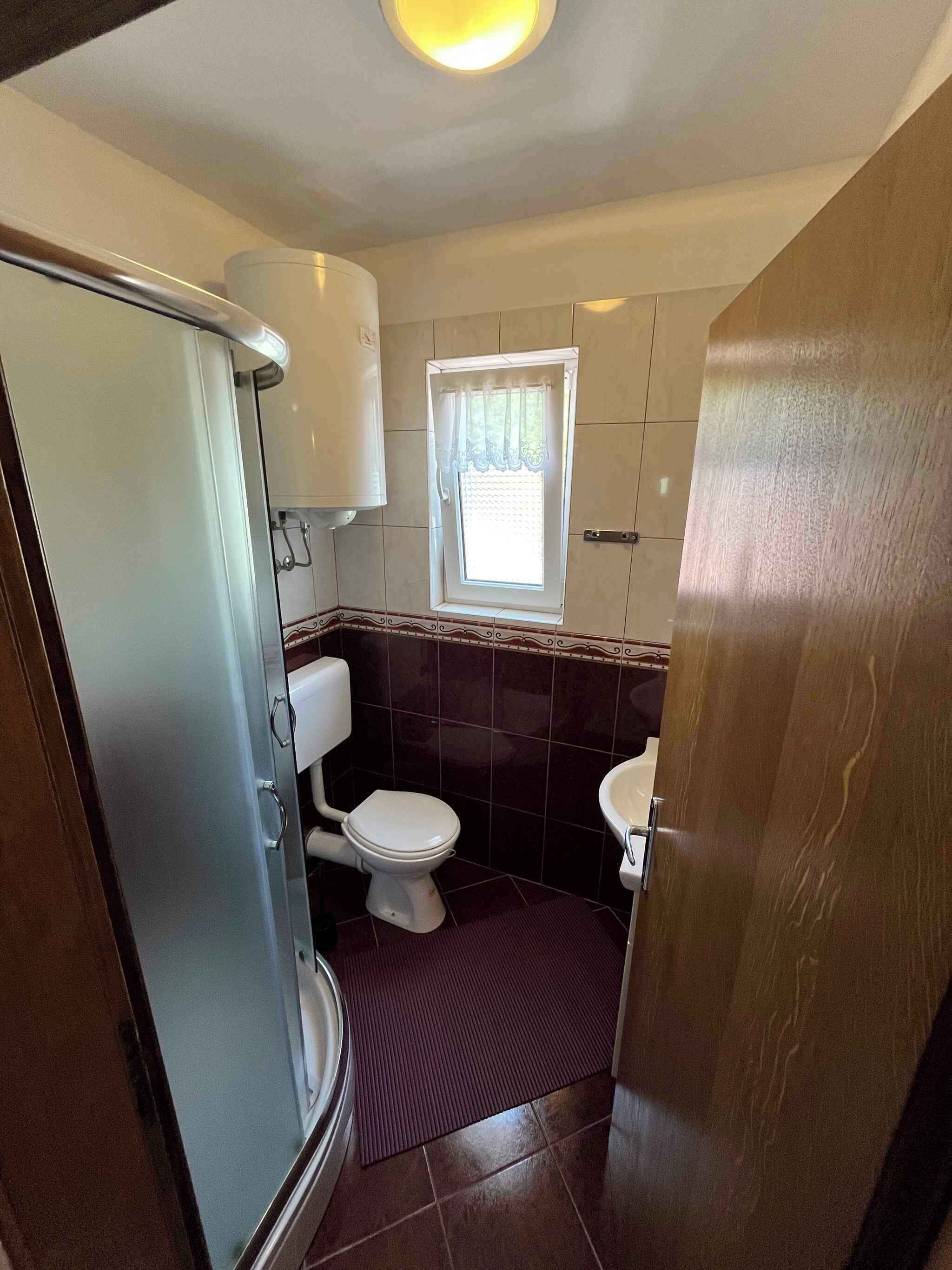 Une petite salle de bain comprenant des toilettes, un lavabo et une douche.