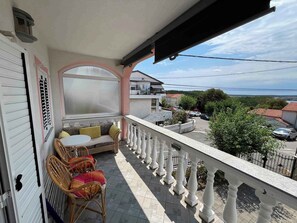 Un balcon doté d’un espace salon, offrant une vue sur la rue et muni d’une rambarde.