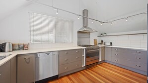 Una cocina moderna con lavavajillas, estufa, horno y ventana con persianas.