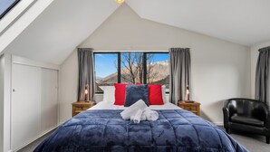 A bedroom with a large bed, a view of mountains, and a skylight.