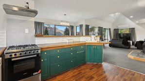 A modern kitchen with a gas stove, green cabinets, and a large island.