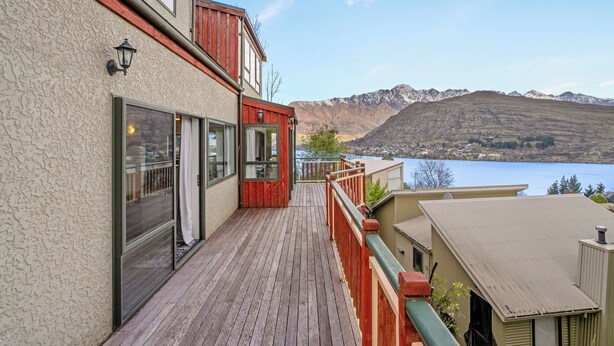 A wooden deck with a view of mountains and a lake.