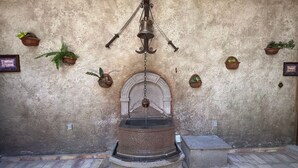 A stone well with a bell and a pulley system, surrounded by potted plants and a rustic wall. - Casa Turicum Val'Quirico Centro (Val'Quirico)