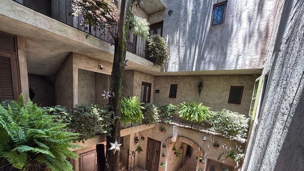 A courtyard with multiple balconies, potted plants, and a central tree. - Casa Turicum Val'Quirico Centro (Val'Quirico)