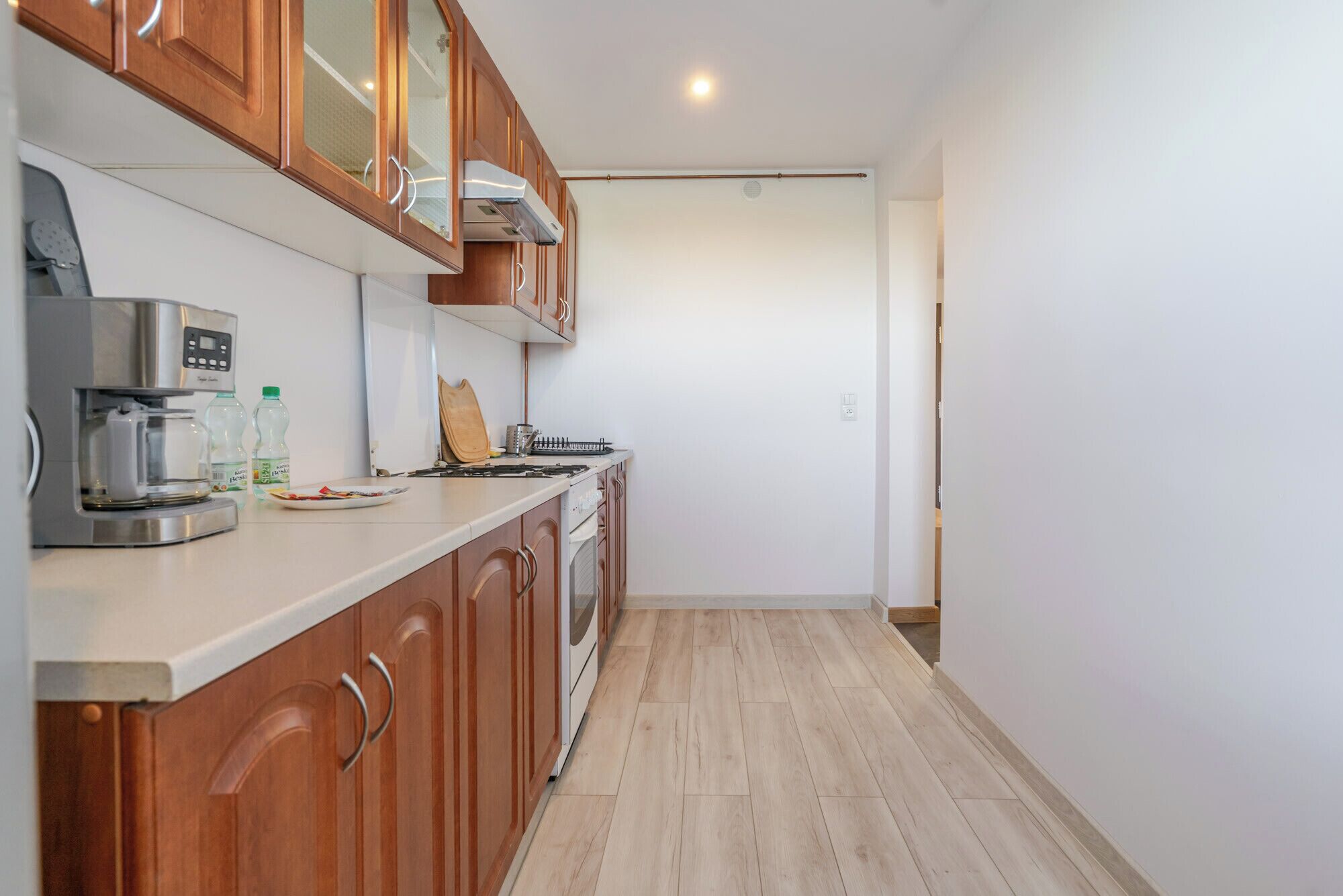 A modern kitchen with wooden cabinets, a coffee machine, and a stove.