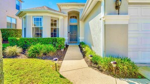 A residential house with a front entrance, a driveway, and a well-maintained lawn.