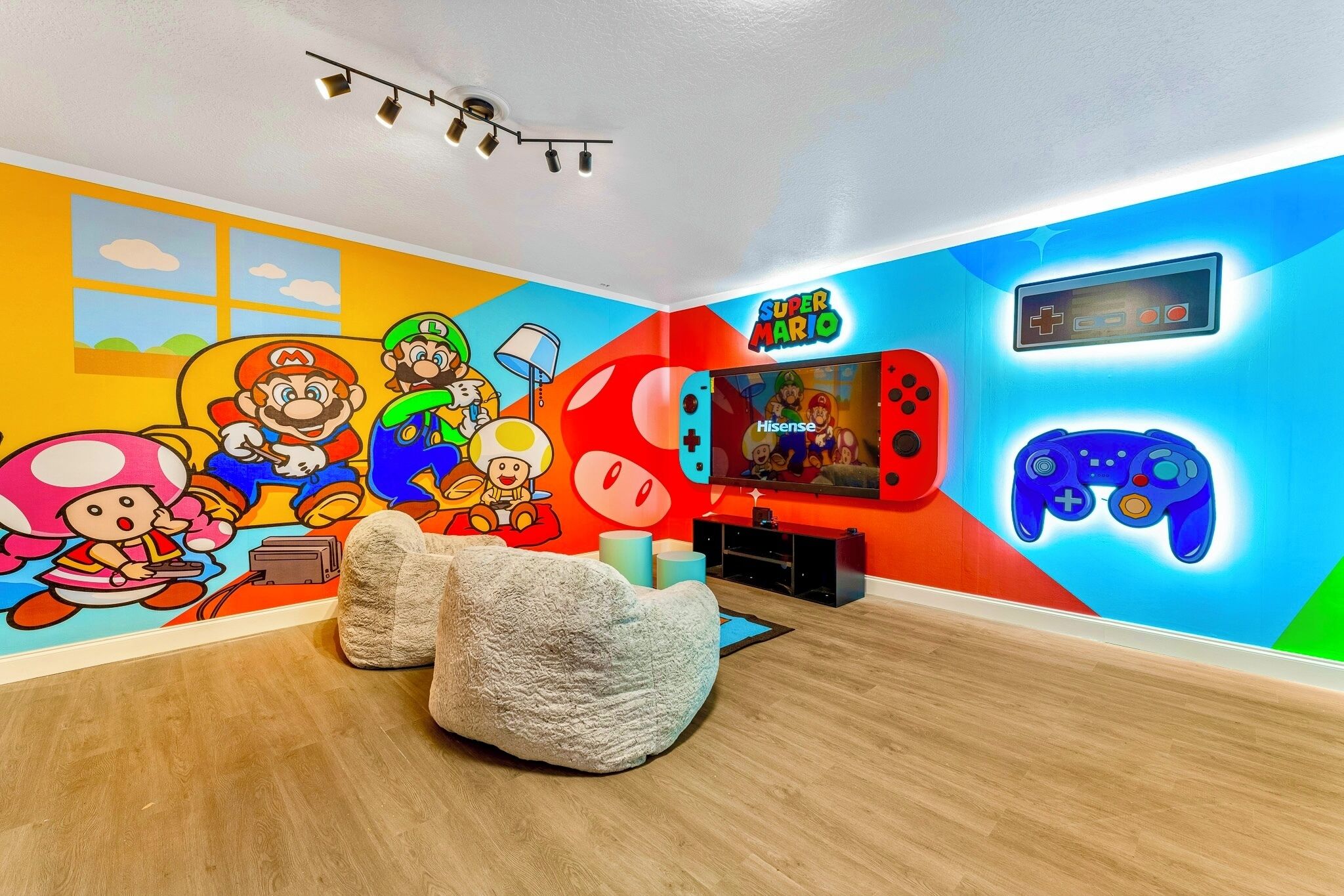 A room with a colorful mural, a television, and gaming consoles.