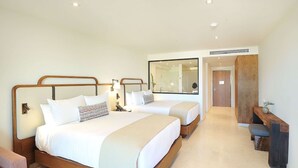 A hotel room with two beds, a desk, and a mirror.