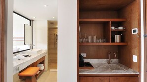 A modern bathroom with a marble sink, wooden vanity, and a built-in shelf with glassware and toiletries.