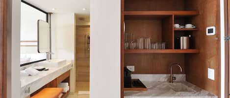 Une salle de bain moderne avec un lavabo en marbre, un meuble-lavabo en bois et une étagère intégrée où sont rangés des articles de toilette et de la verrerie.