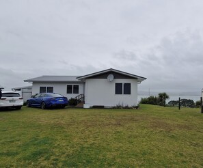 A modern two-story house with a white exterior, a satellite dish, and a garage. - Glorious views and relaxation a plenty (Kawhia)