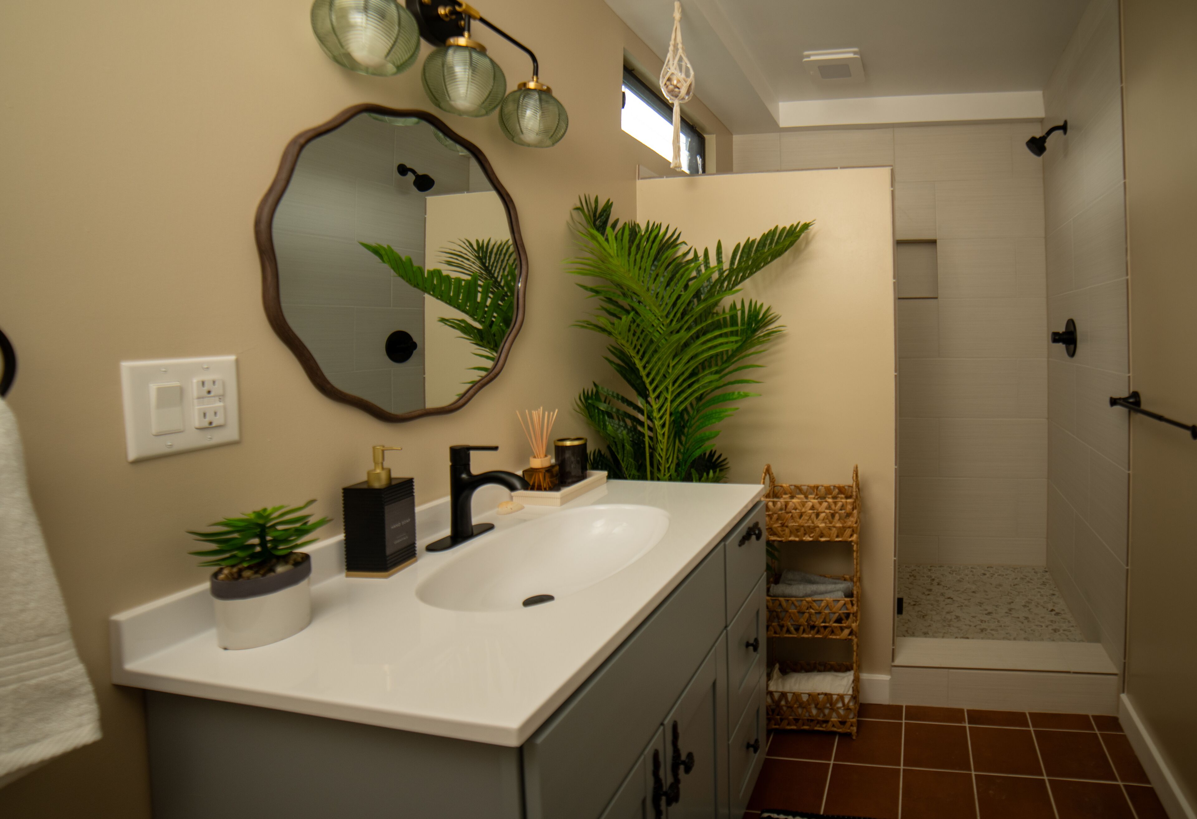 A bathroom with a sink, mirror, and shower.