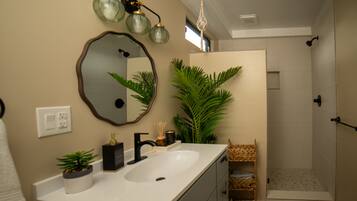 A bathroom with a sink, mirror, and shower.