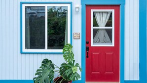 A building with a red door and a window with a blue frame. - Beautiful Apartment in Hawaii (Captain Cook)